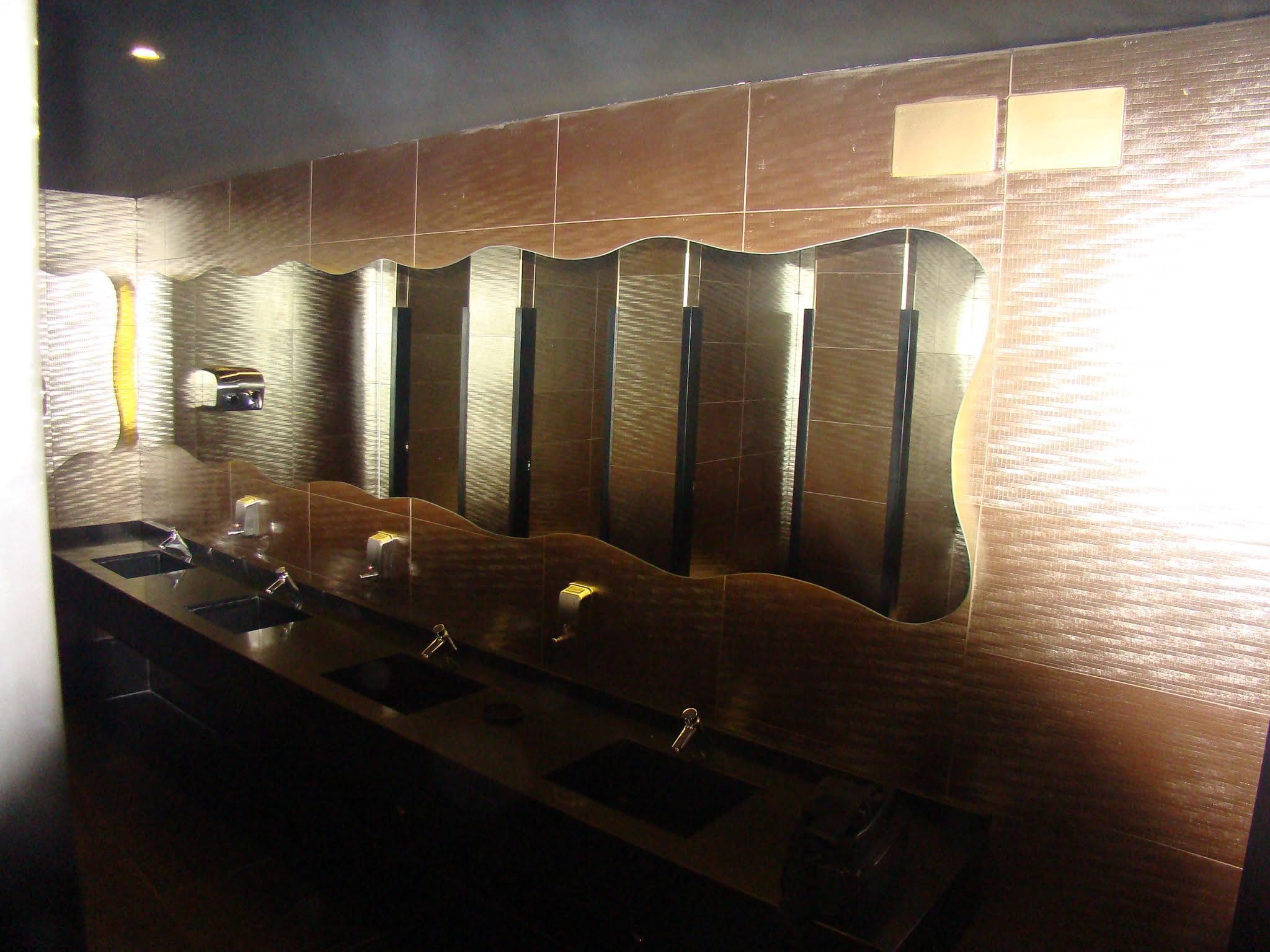 Baño de discoteca con revestimiento oscuro e iluminación ambiental.